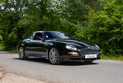 a black sports car driving down the road in the woods