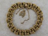 a close up of a gold chain bracelet with a leaf on it