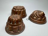 three metal cake pans sitting on top of a white surface