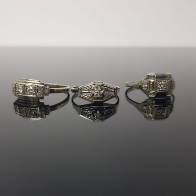 two rings with diamonds on a reflective surface