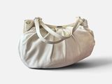 Le grand sac blanc est posé par terre, près d'un mur blanc.