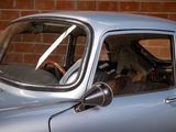 a small blue car parked in front of a brick wall