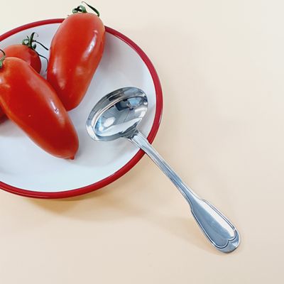 tomatoes on a plate with a spoon and spoon rest on a table