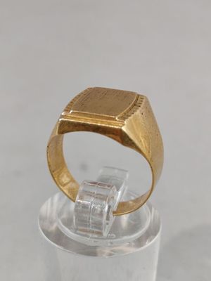 a gold signet ring on a clear glass holder