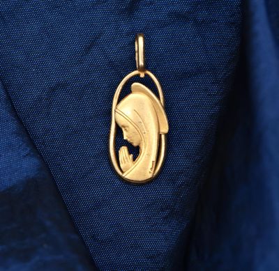 a close up of a gold fish pendant on a blue shirt