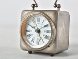 a small silver clock with roman numerals on it