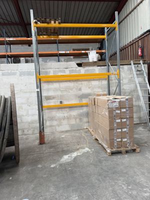 boxes are stacked on pallets in a warehouse with a ladder