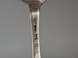 a silver spoon with a bird on it sitting on top of a table