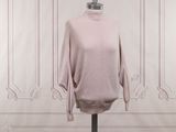 pink turtle neck sweater on a mannequin stand in front of a white wall