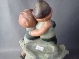a figurine of a boy and a girl hugging on a rock