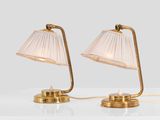 a pair of brass table lamps with plea lampshads