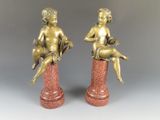 paire de figurines anciennes en bronze représentant un garçon et une fille assis sur un socle