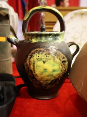 une théière marron et jaune posée sur une table rouge