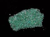close up of a pile of green crushed glass on a black surface