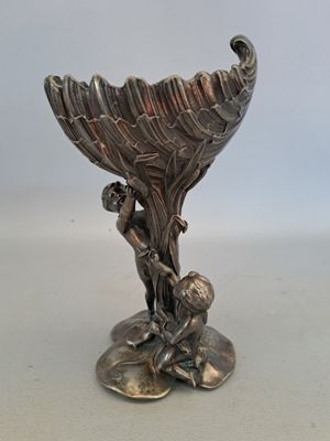 un vase en argent orné d'un oiseau, posé sur une table