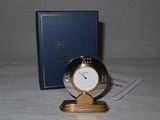 a small clock sitting on a table next to a book