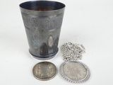 a silver cup with a chain around it and a coin next to it