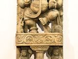 statue of a seated gan on a pedestal in a white room