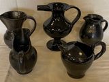 quatre vases noirs posés sur une table, sur fond blanc