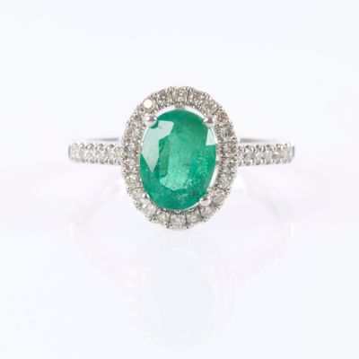 a close up of a ring with a green stone surrounded by diamonds