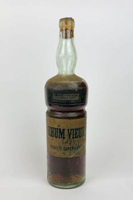 une vieille bouteille d'alcool posée sur une surface blanche