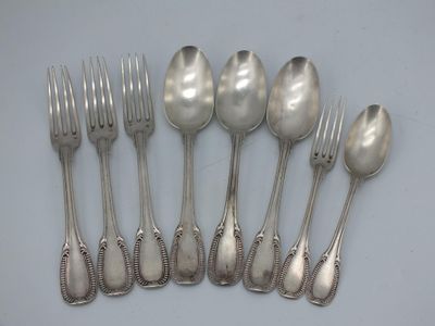 six silverplated spoons and six forks on a white surface