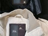 three jackets and a passport sitting on a bed