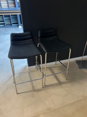 deux tabourets de bar en cuir noir dans une pièce dont l'un des murs est noir