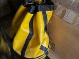 un sac jaune et noir posé sur une palette à côté d'une pile de cartons
