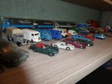 Des petites voitures et des camions sont alignés sur une table en bois