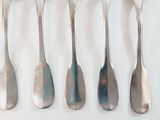 five spoons and a fork on a white surface