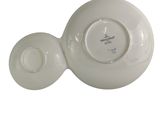 a white bowl and saucer sitting on a white surface
