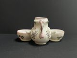 three cups and a teapot sitting on a table