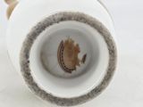a close up of a white vase with a brown spot on it