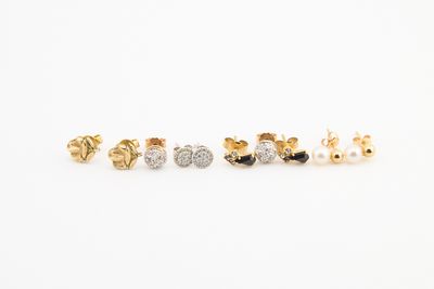 trois paires de boucles d'oreilles à clous en or et en argent sur fond blanc