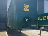 un grand camion vert garé devant un immeuble