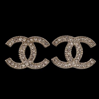 a pair of chanel earrings on a black background
