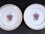 deux assiettes blanches bordées d'or et ornées d'un blason bleu et rouge
