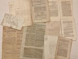Plusieurs pages de vieux papiers sont posées sur une surface blanche