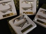 three silver metal birds on display in a box on a black surface