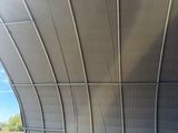 a large metal structure with a metal roof over a field