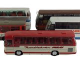 Quatre petits bus sont alignés en rang sur une surface blanche