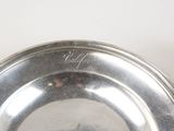 a silver plate on a white table with a black cat on it