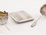 a silver cup, spoon, and spoon rest on a white surface