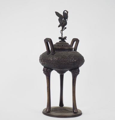 un vieux vase en bronze surmonté d'un oiseau