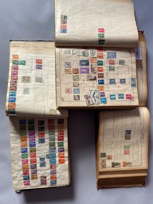 trois livres ouverts, sur lesquels sont apposés des timbres, posés sur une surface bleue