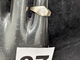 une main à laquelle est passée une bague sur laquelle figure un chiffre