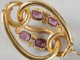 a close up of a gold brooch with pink stones on it