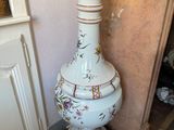 a tall vase sitting on a wooden stand in a room