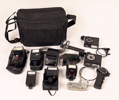a black bag with a camera, flash, camera and other items